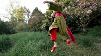 girl in green and red dress standing on green grass field