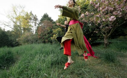 girl in green and red dress standing on green grass field