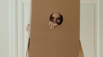 girl in white dress holding brown cardboard box