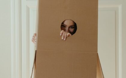 girl in white dress holding brown cardboard box