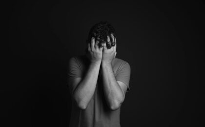 gray scale photo of man covering face with his hands