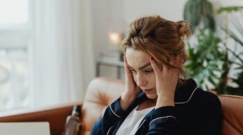 woman wearing a pajama holding her head