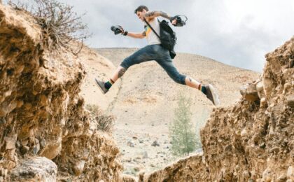 active man jumping over rocky formations