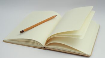 white notebook and yellow pencil