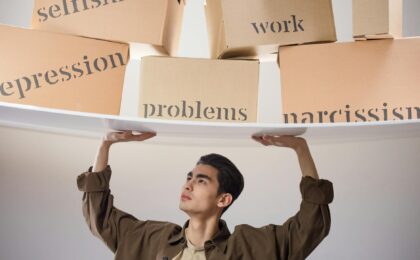 man standing with arms raised and holding boxes with problems
